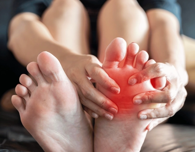 Close-up of feet with hands pressing the forefoot, illustrating ball-of-foot pain or inflammation.