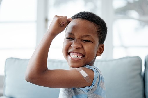 Young African American boy posing with band-aid on arm from immunization